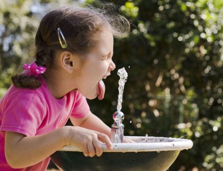 little girl drinking from water fountain